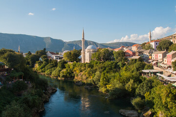 Fototapeta na wymiar Beautiful view on Mostar city with old bridge, mosque and ancient buildings on Neretva river in Bosnia and Herzegovina. popular tourist destination.