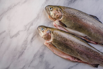 fresh rainbow fish trout on black stone background with vegetables 