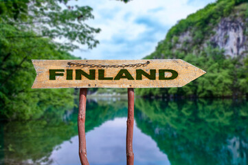 Finland wooden arrow road sign against lake in the forest background. Travel to Finland  concept.