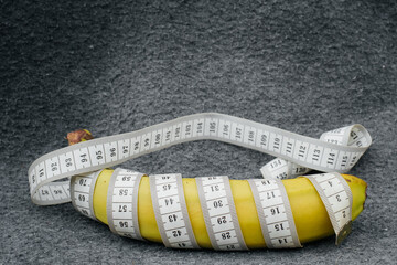 banana and measuring tape large on a gray background