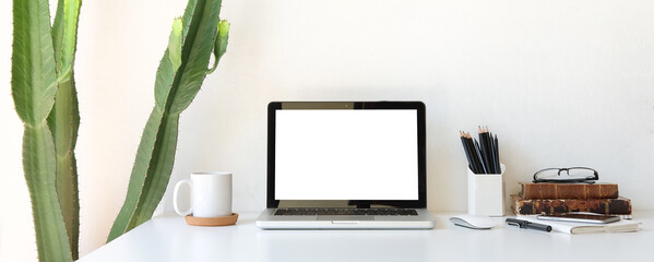 Cropped shot of modern workspace with blank screen laptop on white table.
