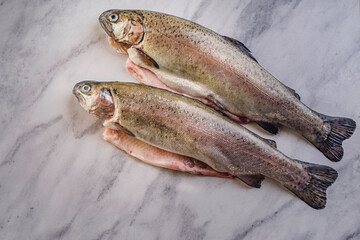 fresh rainbow fish trout on black stone background with vegetables 