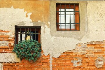 Fototapeta na wymiar old window in the wall. Stained glass windows on an ancient ancient brick Italian wall. Venetian architectural landscape. Ruins of antiquity.