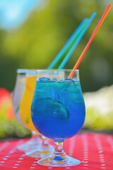 Three ice soft drinks with soda water, refreshing summer beverage. Alcohol cocktail with ice in a glass outside.