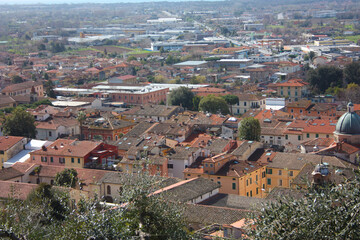 Fototapeta na wymiar the red roofs of the inhabited houses, the church and the bell tower of the pietrasanta cathedral seen from the green of a hill at the top