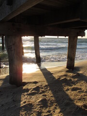 Calm sea waves under a wooden bridge. This image can be used for an article about dream interpretation. Being under the bridge in a dream means that someone is unable to overcome problems in life.