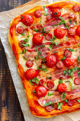 Pizza with bacon, sausage, mozzarella, tomatoes and basil. Italian cuisine. Recipe.