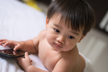 Little boy playing smartphone on the bed