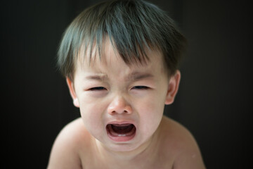 An Asian boy is crying on a black background