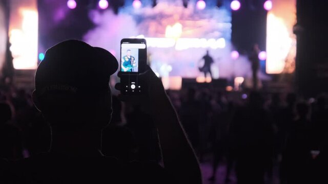 Silhouette of Fans near Stage are Filming Concert. Making Video with Smartphone