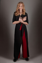 Fototapeta premium A slender girl in black and red clothes on a gray background.