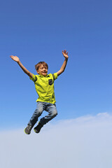 Junge springt in die Luft, im Hintergrund blauer Himmel