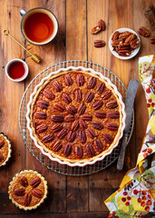 Pecan pie, tart in baking dish. Traditional festive Thanksgiving dessert. Wooden background. Top view.