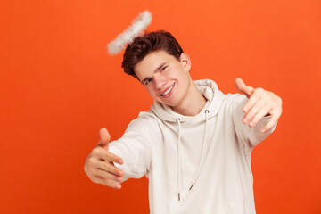 Come here. Handsome friendly man in casual hoodie with nimbus overhead pretending to be angel and...
