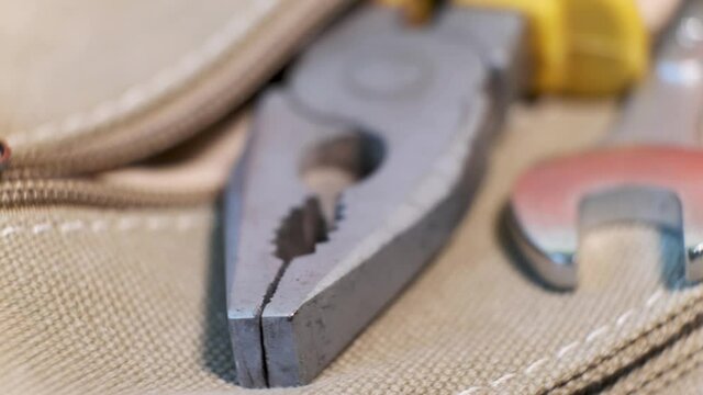 Close-up of locksmith's tool - pliers and a wrench in a canvas bag pocket on a rotating table. Shallow Depth of Field.