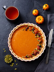 Pumpkin pie on marble board with cup of tea. Grey background. Close up. Top view.