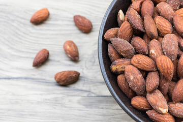 Closeup of almond with salt in black bowl.