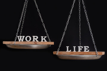 Balance work and personal life. Scales on black background close up