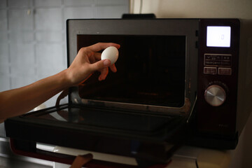 電子レンジで卵を温めようとする男性