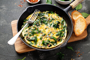 Omelette with baby spinach in cast iron pan, healthy breakfast .