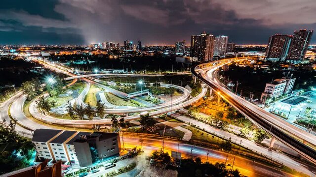 Time-lapse of car traffic transportation on winding highway road intersection in Bangkok city Thailand at night. Public transport, commuter lifestyle, Asian city life concept. High angle view zoom out