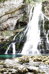 Schöner verzweigter Wasserfall stürzt über Felsen herunter mit nassen Steinen im Vordergrund