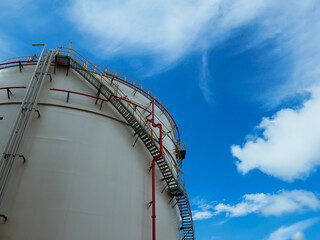 White chemical storage tanks with spiral ladder against blue sky background.
