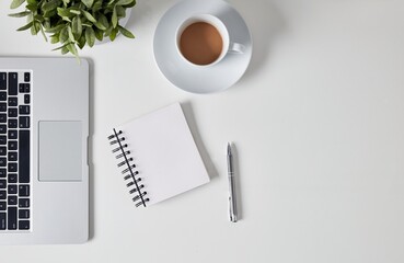Top view of home office desk workspace with coffee and supplies, blank notepad in the middle. Modern minimal design desktop. Copy space for text.
