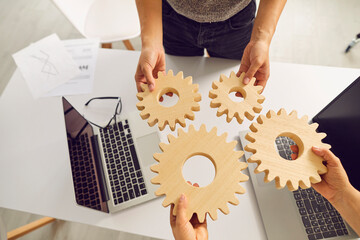 Teamwork, cooperation and successful strategy concept. hands of business people with gears, top view