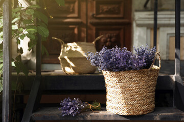 Wicker basket with beautiful lavender flowers on metal stairs near building