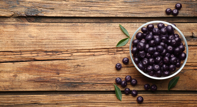 Fresh acai berries on wooden table, flat lay. Space for text