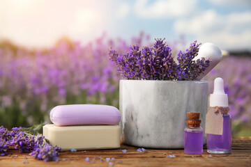 Composition with fresh lavender flowers and cosmetic products on wooden table outdoors, closeup