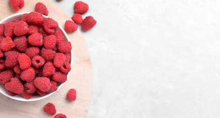 Delicious fresh ripe raspberries on light marble table, flat lay. Space for text