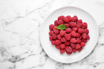 Delicious fresh ripe raspberries in plate on white marble table, top view. Space for text