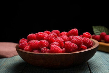 Delicious fresh ripe raspberries in plate on blue wooden table