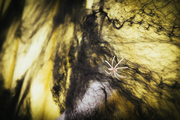 toy spider on a black web on a yellow background, Halloween