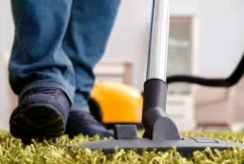 The man cleaning the floor carpet with a vacuum cleaner close up