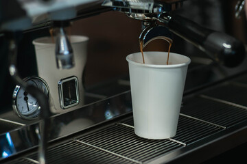 The process of making coffee on a coffee maker. The coffee is spilled from the holder into a paper cup.