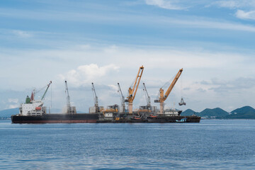 Obraz premium Ship during loading rice by crane at sea.