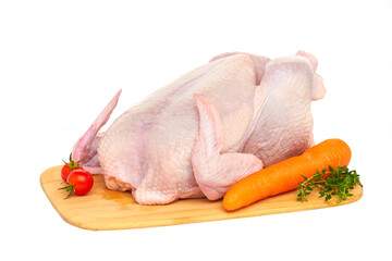 Fresh raw chicken carcass on a wooden cutting Board with vegetables and herbs, on a white background.