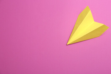 Yellow paper plane on purple background, top view. Space for text