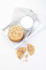 Oatmeal and red quinoa cookies with glass of milk, on wooden tray, vertical, top view