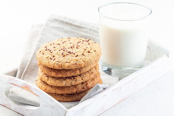 Oatmeal and red quinoa cookies with a glass of milk, on wooden tray, horizontal