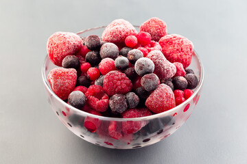 Frozen berries in a glass bowl, raspberry, strawberry, cranberry and black currant, horizontal, closeup