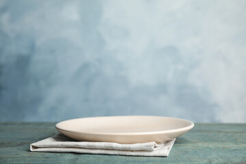 Empty plate and towel on light blue wooden table. Space for text