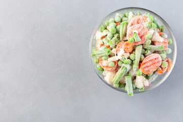 Bowl with frozen vegetables, green peas, carrot, cauliflower,  green beans, horizontal, copy space, top view