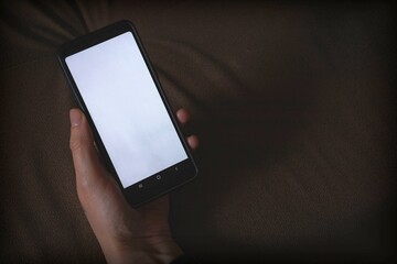 Smartphone mockup. A hand holds a black telephone with a white screen. Copy space