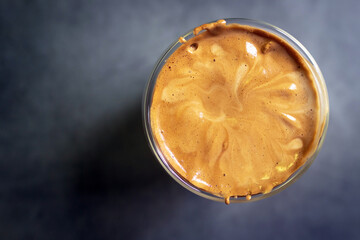 Dalgona Coffee; fluffy whipped coffee on milk. Coffee is a beverage made by whipping equal proportions of instant coffee, sugar and hot water until it becomes creamy. Top view
