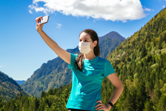Stock photo of a young woman wearing a mask taking a selfie in the mountains and beautiful landscapes