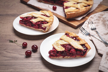 Slices of delicious fresh cherry pie served on wooden table, closeup